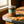 A glass jar candle with a silver metal lid and a teal label reading 'DEAR ALIEN' sits on a patterned table in a warm indoor setting near a window.