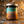 A glass jar candle with a silver metal lid and a colorful label reading 'DEAR ALIEN' and 'LAST LOOKS GROOMING CO.' sits on a speckled stone surface with a terrazzo-style background.